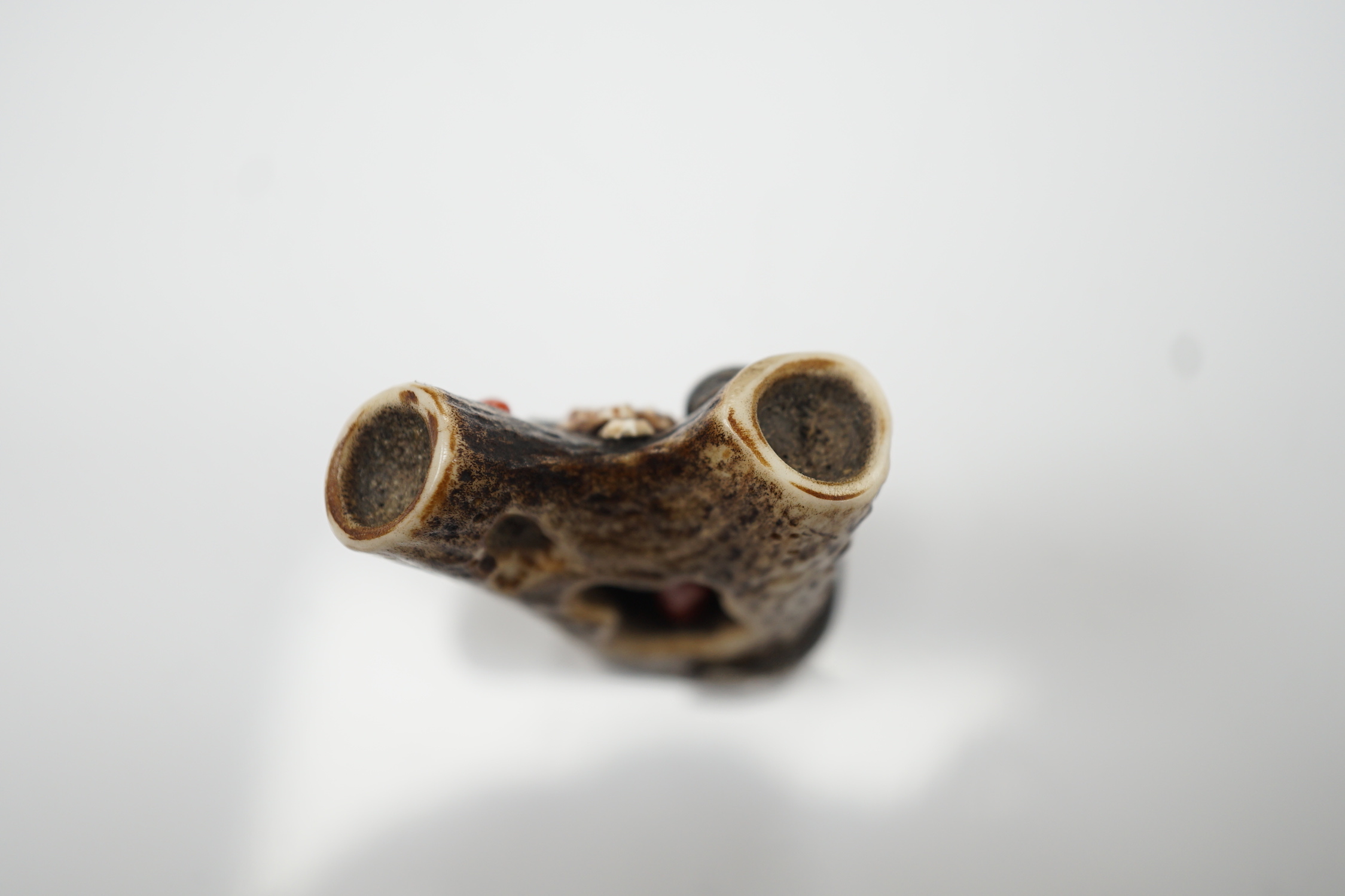 A Japanese coral and mixed metal mounted stag antler netsuke, 19th century, the antler carved in imitation of rocks applied with a white metal seahorse, gilt metal scallop shell, carved bone barnacles, the underside holl
